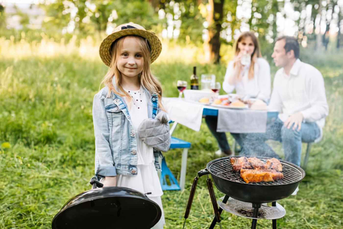 Girl at grill with parents in the background